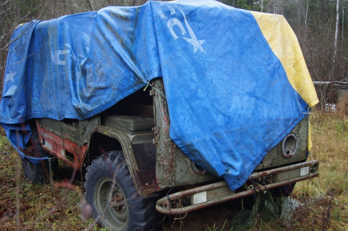 Ett till gammalt militärfordon som är täckt med en presenningen 